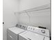 Functional laundry room with side-by-side washer and dryer and wire shelving at 12843 Madison Pointe # 208, Orlando, FL 32821