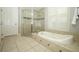 Beautiful bathroom featuring a soaking tub, glass enclosed shower, and neutral tile at 14252 Anastasia Ln, Orlando, FL 32828