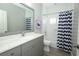 Stylish bathroom featuring gray vanity, a large mirror and shower with patterned curtain at 14252 Anastasia Ln, Orlando, FL 32828