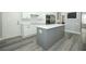Spacious kitchen with white cabinets, stainless appliances, gray island and durable gray hardwood floors at 14252 Anastasia Ln, Orlando, FL 32828