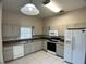 Well-lit kitchen featuring white appliances, tile flooring, and light countertops at 1433 Bluff Loop, Dundee, FL 33838