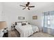 Cozy bedroom with a ceiling fan, white bedding, patterned curtains, and bedside lamps at 15343 Lebeau Loop, Winter Garden, FL 34787
