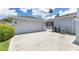 Attached two-car garage with brick-paved driveway, side entrance gate, and tropical landscaping at 157 Bell Tower E Xing, Kissimmee, FL 34759
