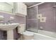 Bathroom showcasing purple tiling, a pedestal sink, and a shower-tub combination with a sliding glass door at 1746 Valley Forge Road, Orlando, FL 32806