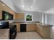 This kitchen features neutral tile flooring, bright wood cabinetry, and black appliances at 1877 Courtland Blvd, Deltona, FL 32738