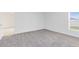 A bright bedroom with neutral carpet, a window bringing in natural light, and a door leading to another room at 200 Garnet Ave, Kissimmee, FL 34758