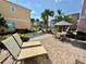 Relaxing patio area featuring a table, chairs, lounge chairs and colorful buildings in the background at 3004 Latitude Ln, Kissimmee, FL 34747