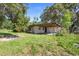 View of the back exterior with a large covered patio surrounded by a grassy yard and mature trees at 321 Beard Rd, Winter Garden, FL 34787