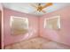 A bedroom with pink walls, two windows, a ceiling fan, and worn carpet at 321 Beard Rd, Winter Garden, FL 34787