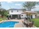Spacious backyard featuring a swimming pool, outdoor dining area, solar panels, and mature trees at 4536 Misty Morn Cir, Orlando, FL 32812