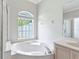 Bright bathroom features a large soaking tub, arched window, and natural light at 460 Suncrest Ct, Oviedo, FL 32765