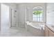 Bright bathroom features a large soaking tub, glass enclosed shower, and arched window at 460 Suncrest Ct, Oviedo, FL 32765