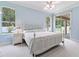 Light blue bedroom features a white bed frame, ceiling fan, and a view of the backyard at 460 Suncrest Ct, Oviedo, FL 32765