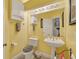 Bright yellow bathroom features a toilet, pedestal sink, and mirrored vanity with overhead lighting at 5704 Bay Side Dr, Orlando, FL 32819