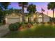 Charming home at dusk featuring a manicured lawn, palm trees, and vibrant landscaping at 5704 Bay Side Dr, Orlando, FL 32819