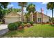 Charming home featuring a manicured lawn, palm trees, and vibrant landscaping at 5704 Bay Side Dr, Orlando, FL 32819