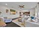 Bright living room with hardwood floors leads to the kitchen and features white furniture and stylish decorations at 7895 Pleasant Pine Cir, Winter Park, FL 32792