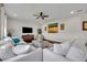 Bright living room features hardwood floors, a modern ceiling fan, comfortable white furniture, and decorative artwork at 7895 Pleasant Pine Cir, Winter Park, FL 32792