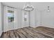 Open-concept living room featuring wood flooring, large windows with white curtains, and modern lighting at 840 Livestock Loop, St Cloud, FL 34771