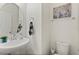 Stylish half bathroom with a round mirror, pedestal sink, and modern decor at 9814 Amber Chestnut Way, Winter Garden, FL 34787