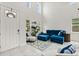 Bright living room with high ceilings, large windows, and stylish blue furniture on white tile floors at 9814 Amber Chestnut Way, Winter Garden, FL 34787