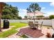 Relax on the backyard brick patio under the umbrella next to the white fence and grill in this charming outdoor space at 999 Mancha Real Dr, Orlando, FL 32807