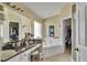 Well-lit primary bathroom with a soaking tub, dual vanity, and separate walk-in closets at 1019 Lake Berkley Dr, Kissimmee, FL 34746