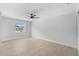Bright bedroom with wood-look flooring, ceiling fan, and a large window overlooking the front yard at 105 E Magnolia St, Davenport, FL 33837