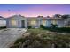 Twilight view of a cozy home, showcasing its painted brick facade and well-maintained front yard at 105 E Magnolia St, Davenport, FL 33837
