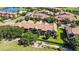 Aerial view of condo buildings with tile roofs overlooking a lake and golf course at 10653 Belfry Cir, Orlando, FL 32832