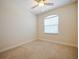 Clean, empty bedroom with neutral carpet, ceiling fan, and window bringing natural light at 10653 Belfry Cir, Orlando, FL 32832