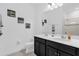 Bathroom featuring double sinks, black cabinets, and a large mirror at 1156 Cavender Creek Rd, Minneola, FL 34715