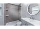 Bathroom showcasing a glass-enclosed shower, large format gray tiling and a modern vanity with round mirror at 1209 Russell Dr, Ocoee, FL 34761