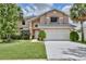 Charming two-story home with a manicured lawn, complemented by lush landscaping and a spacious two-car garage at 14332 Grassy Cove Cir, Orlando, FL 32824