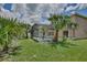 Backyard view of a screened pool surrounded by lush tropical landscaping and green grass at 14332 Grassy Cove Cir, Orlando, FL 32824