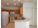 Efficient kitchen featuring wood cabinets, white appliances, and a breakfast bar for casual dining at 2406 Grand Central Pkwy # 14, Orlando, FL 32839