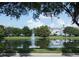 Pond with fountain surrounded by blue townhomes and a clear blue sky at 2406 Grand Central Pkwy # 14, Orlando, FL 32839