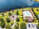 Aerial view of a community pool and playground area by a lake, with lounge chairs, palm trees, and walking paths at 251 Domus Ln, Casselberry, FL 32707