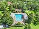 A serene community pool is shown from above, set amidst lush greenery for a relaxing oasis at 2563 Breezy Meadow Rd, Apopka, FL 32712