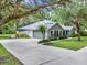 View of home featuring a long driveway, two-car garage, and mature landscaping at 2563 Breezy Meadow Rd, Apopka, FL 32712