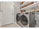 Functional laundry room with front loading washer and dryer, tile flooring, and white shelves at 2563 Breezy Meadow Rd, Apopka, FL 32712