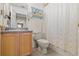 Bright bathroom features a wooden vanity, a toilet, and a shower with patterned curtain at 2850 Spring Heather Pl, Oviedo, FL 32766
