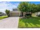 Well-maintained home featuring a brick-paved driveway, lush lawn, mature trees, and a two-car garage at 2850 Spring Heather Pl, Oviedo, FL 32766