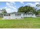 Large backyard with green grass and view of the back of the house, trees and blue skies at 323 Scotland Dr, Daytona Beach, FL 32117