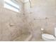 Bathroom featuring a shower and toilet, tiled walls, and window at 323 Scotland Dr, Daytona Beach, FL 32117