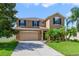 Front exterior of a two-story home with lush landscaping, a driveway, and a two-car garage at 352 Giovani Blvd, Clermont, FL 34715