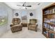 Cozy sitting room features two comfortable chairs, a window for natural light, and a bookcase at 352 Giovani Blvd, Clermont, FL 34715
