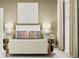 Stylized bedroom featuring a neutral-toned bed, side tables with lamps, and modern art above the bed at 367 Sol Vista Dr, Dundee, FL 33838
