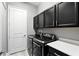 Laundry room with modern black washer and dryer set, complemented by dark cabinets and a white countertop at 3995 Equine Cv, Lake Mary, FL 32746