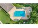 Aerial view of a sparkling community pool surrounded by lounge chairs, lush landscaping, and a building with a roof at 4870 S Semoran Blvd # 1904, Orlando, FL 32822